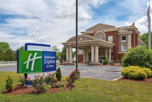 Un hotel con un cartel grande de Holiday Inn Express & Suites, un estacionamiento y un edificio de estilo arquitectónico clásico.