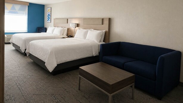 A hotel room with two beds, a blue sofa, a wooden coffee table, and a large window with a view. - Holiday Inn Express Hotel & Suites Murphy by IHG (Murphy)