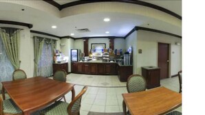 A hotel room with a dining area featuring a wooden table and chairs, a small kitchen area, and a bathroom with a toilet and sink. - Holiday Inn Express Hotel & Suites Murphy by IHG (Murphy)