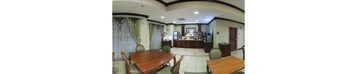 Habitación de hotel con comedor que incluye una mesa y sillas de madera, una pequeña cocina y un baño con inodoro y lavabo.