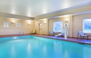 Una piscina con un sillón de salvavidas, un elevador para piscina y una silla con una toalla.