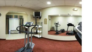 A fitness room with cardio equipment, a television, and a clock on the wall. - Holiday Inn Express Hotel & Suites Murphy by IHG (Murphy)
