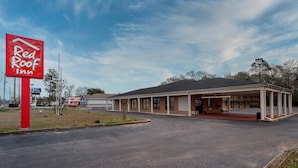 A Red Roof Inn with a single-story building, a covered parking area, and a clear sky.