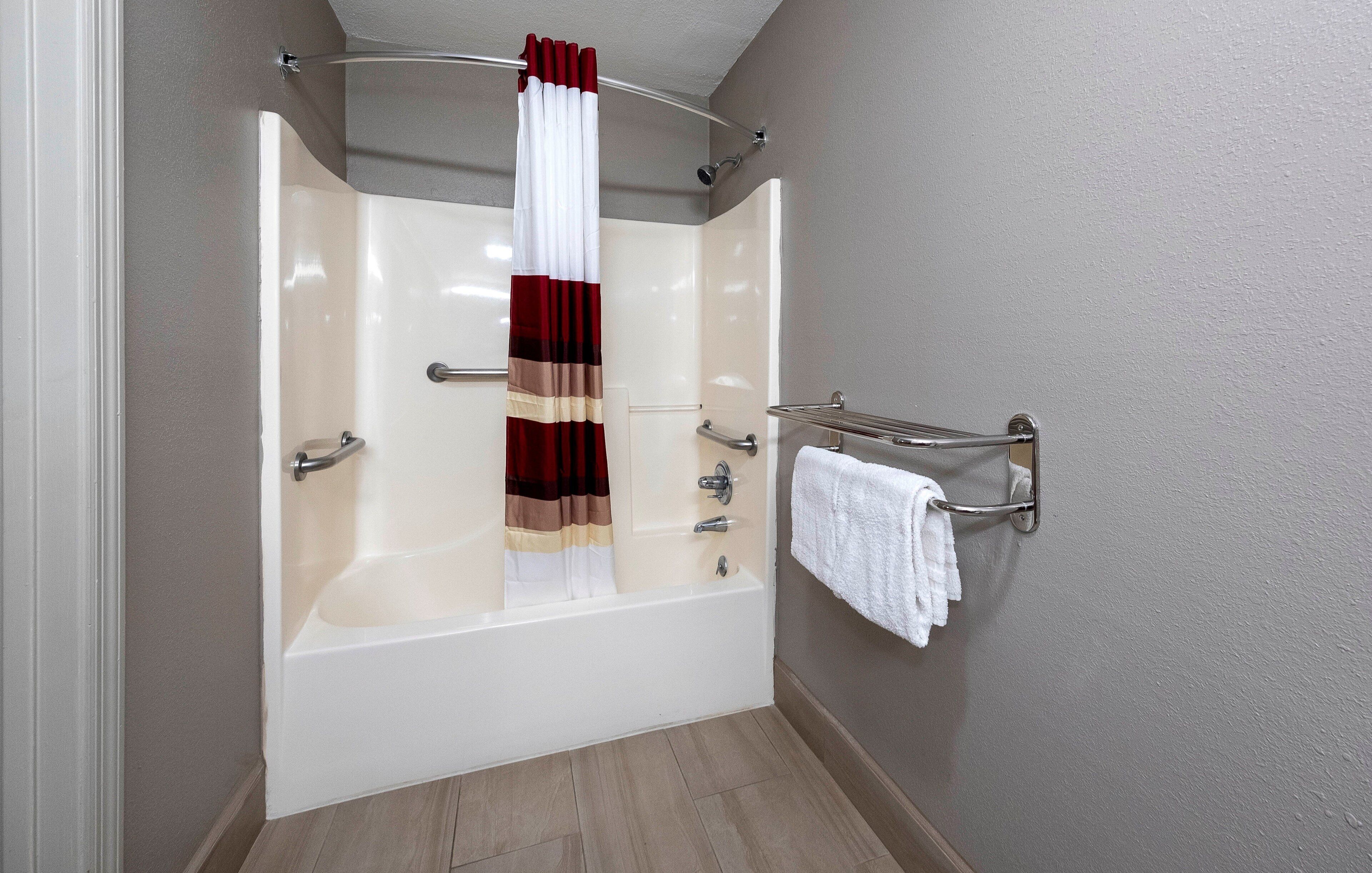 A bathroom with a bathtub, a shower curtain, a towel rack, and a shower head.