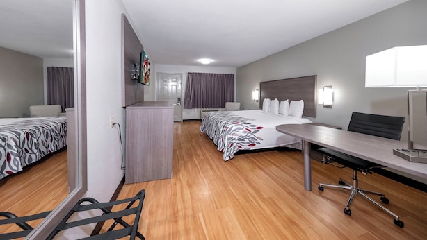 A hotel room with a bed, a desk, a chair, a wardrobe, and a mirror.