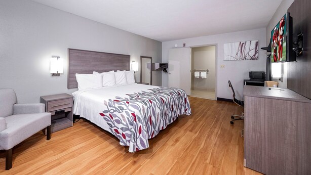 A hotel room with a bed, a desk, a chair, and a TV. - Red Roof Inn Bay Minette (Bay Minette)