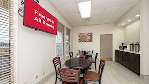 A conference room with a round table, chairs, a TV screen, and a painting on the wall.