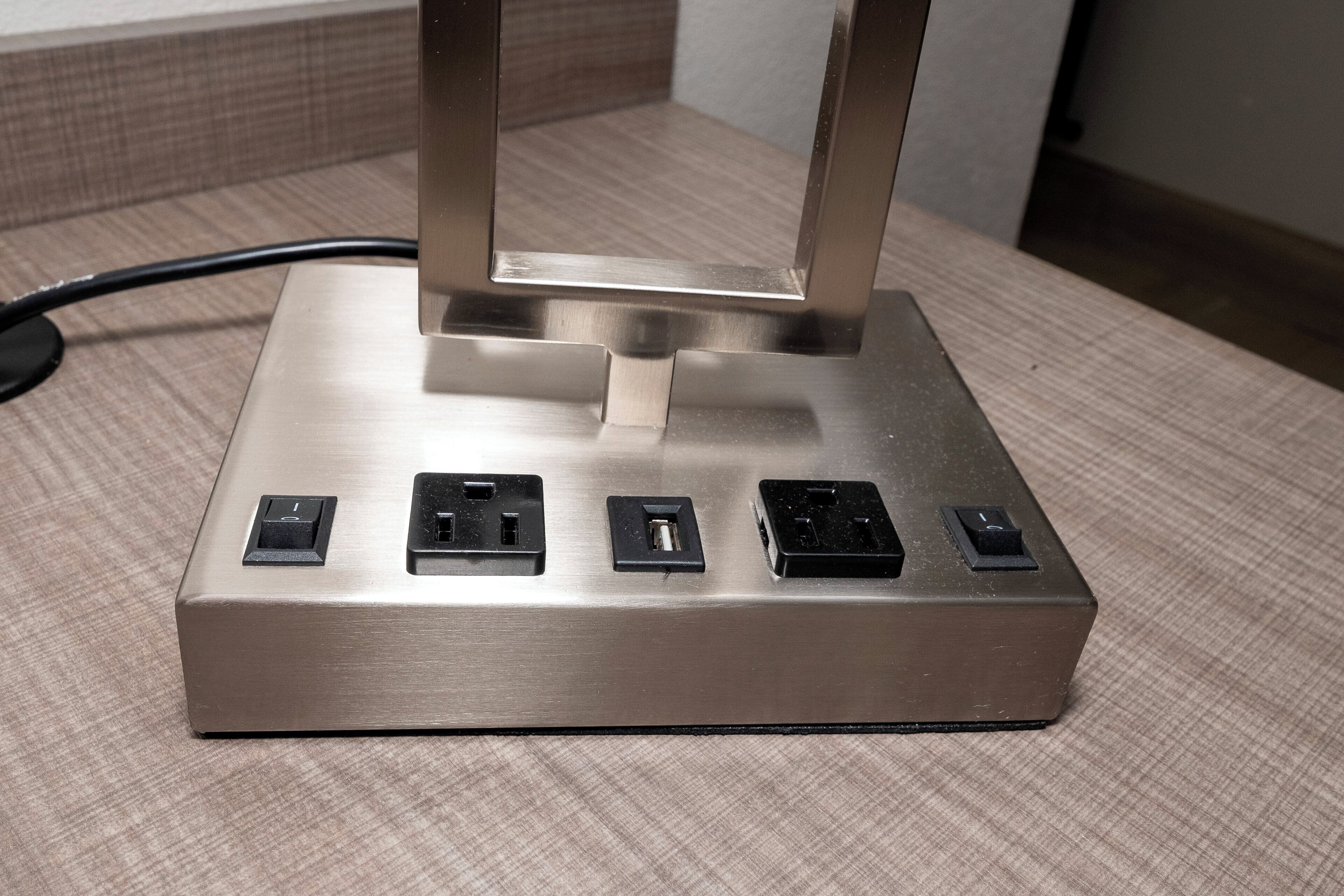 A metallic power strip with five sockets on a textured surface.
