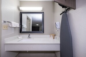 A bathroom with a white sink, a mirror, a towel rack, a shower curtain, and a hand dryer. - Red Roof Inn Bay Minette (Bay Minette)