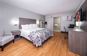 A modern hotel room with a large bed, a desk, a chair, and a wardrobe. - Red Roof Inn Bay Minette (Bay Minette)