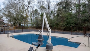 A swimming pool with a lifeguard stand, a diving board, and a metal fence surrounding the area. - Red Roof Inn Bay Minette (Bay Minette)