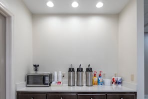 A kitchenette with a microwave, coffee makers, and various coffee and creamer containers. - Red Roof Inn Bay Minette (Bay Minette)