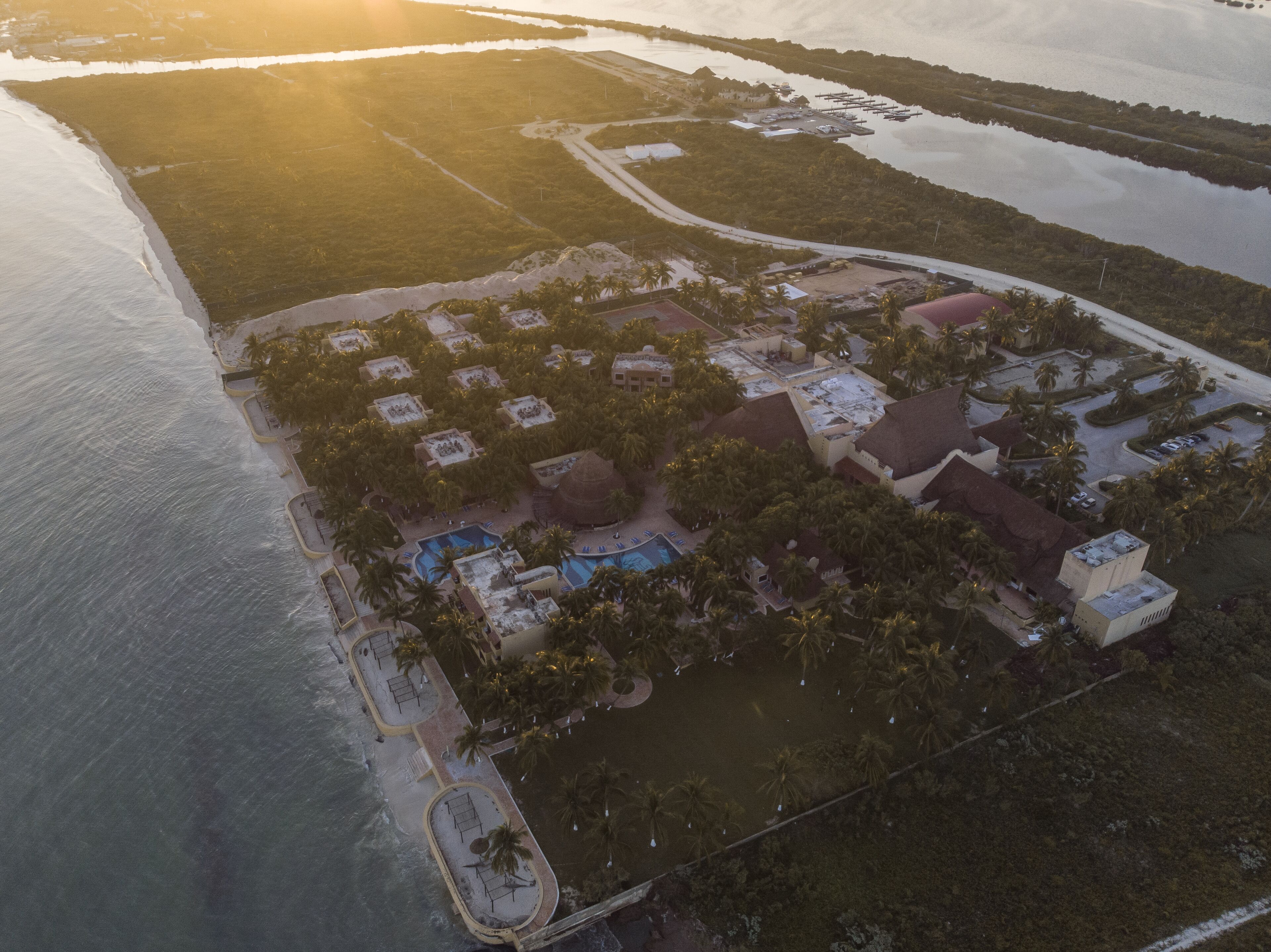 An aerial view of a resort with multiple buildings, a swimming pool, and a beach area.