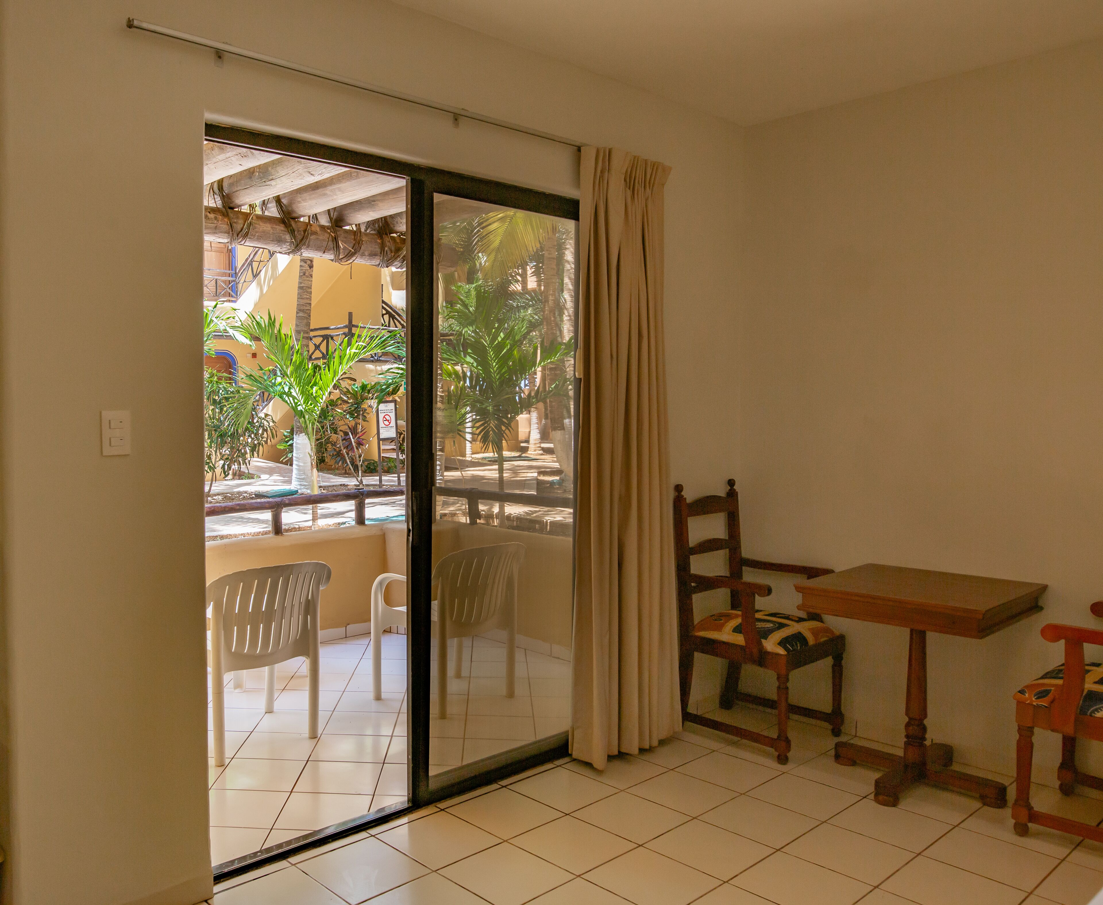A room with a sliding glass door leading to an outdoor area with chairs and a table.