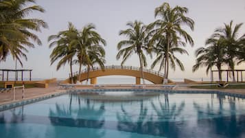 Una piscina al aire libre, sombrillas, sillones reclinables de piscina