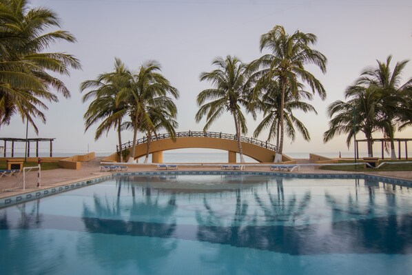 Una piscina al aire libre, sombrillas, sillones reclinables de piscina