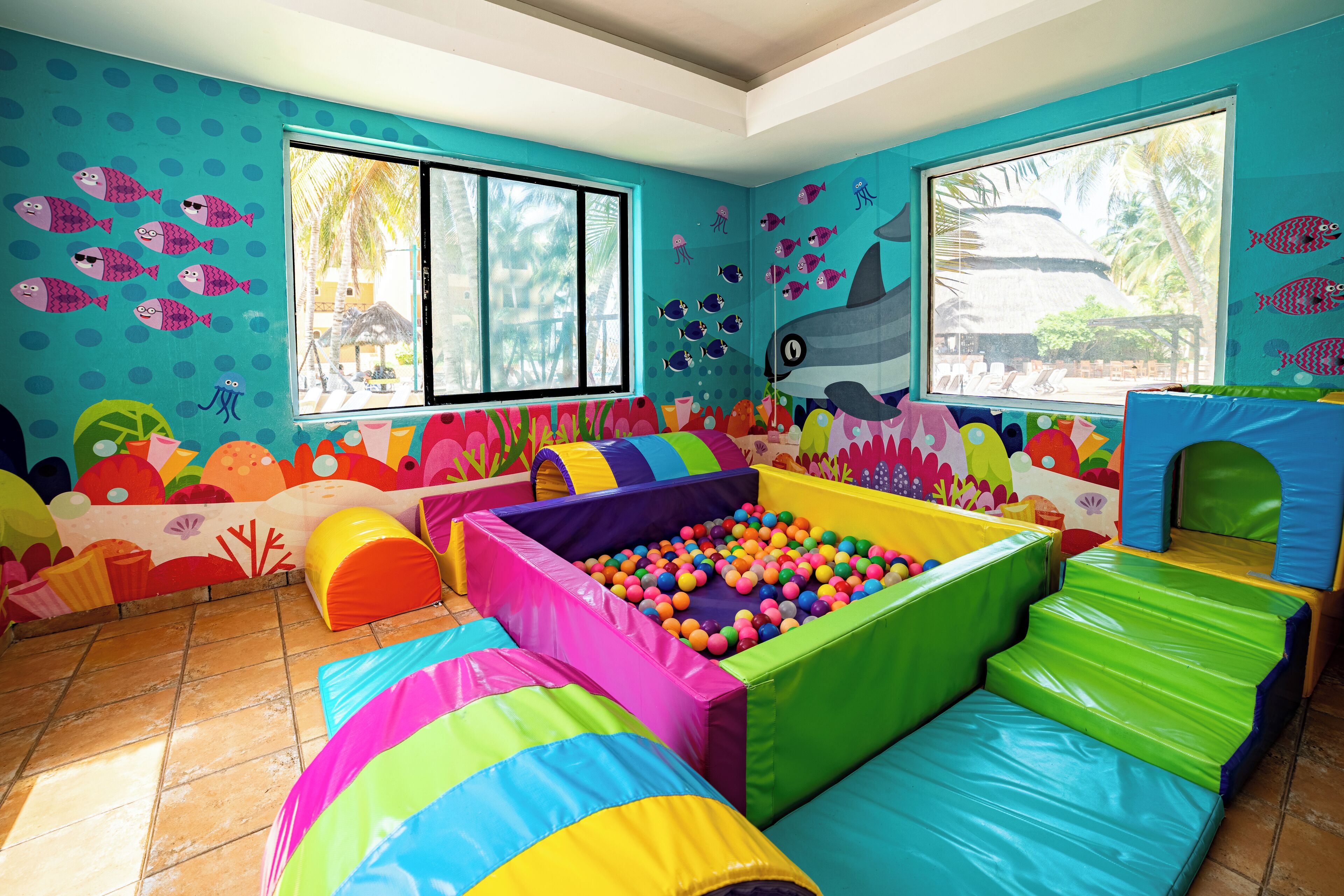 A play area with colorful padded structures and a ball pit, decorated with marine life murals.