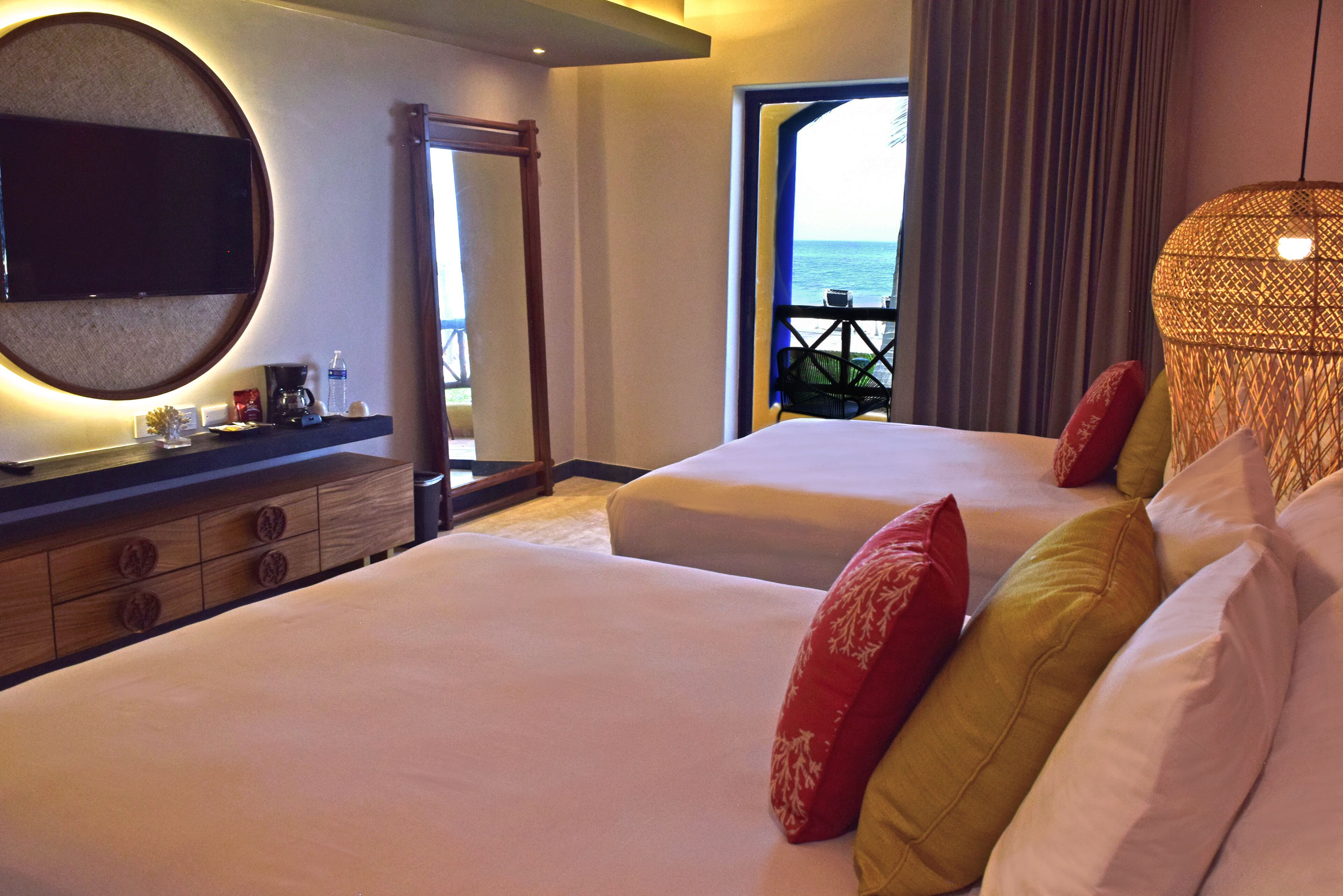 Une chambre d’hôtel avec deux lits, une télévision, un minibar et un balcon donnant sur la mer.