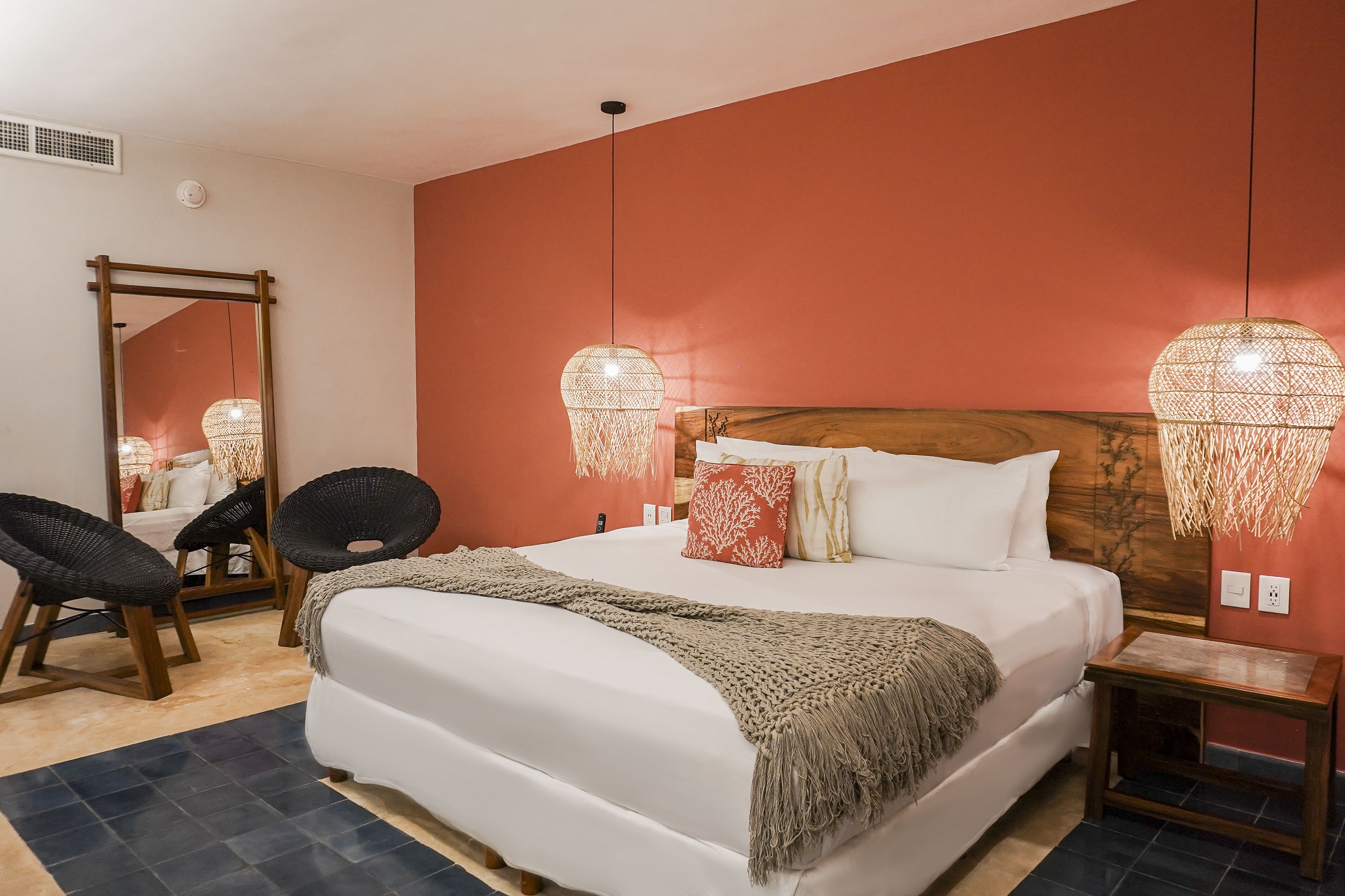 Une chambre à coucher bien rangée, avec un grand lit, deux lampes de chevet, un miroir et une petite table.