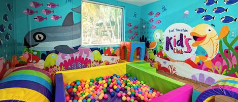 A children's play area with colorful walls, a ball pit, and a shark mural.