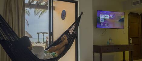 A room with a bed, a TV on the wall, a desk, and a window with curtains.