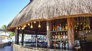 A bar area with a thatched roof, stone walls, and hanging light fixtures. - Reef Yucatan Hotel and Convention Center All Inclusive (Telchac Puerto)