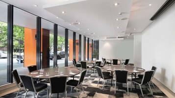 A conference room with round tables, black chairs, and large windows.