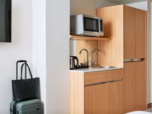 A compact kitchen with a microwave, two stainless steel faucets, and a sink. - Mercure Melbourne Southbank (Southbank)