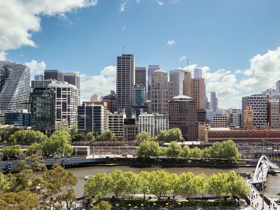 A city skyline with modern buildings, a river, and a bridge.