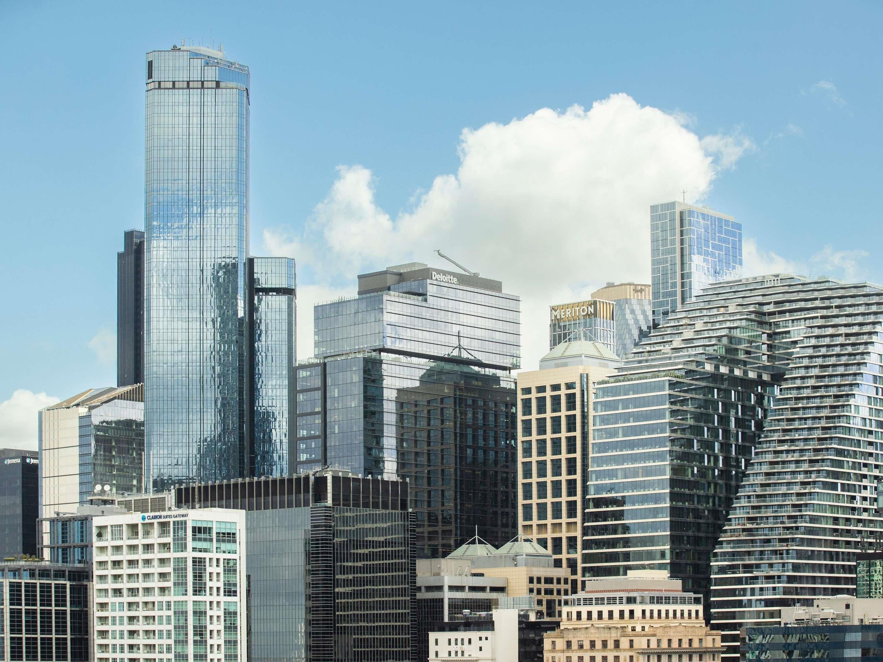 Un paysage urbain avec des immeubles modernes de grande hauteur, dont un bâtiment à la forme incurvée remarquable et plusieurs structures à façade vitrée.
