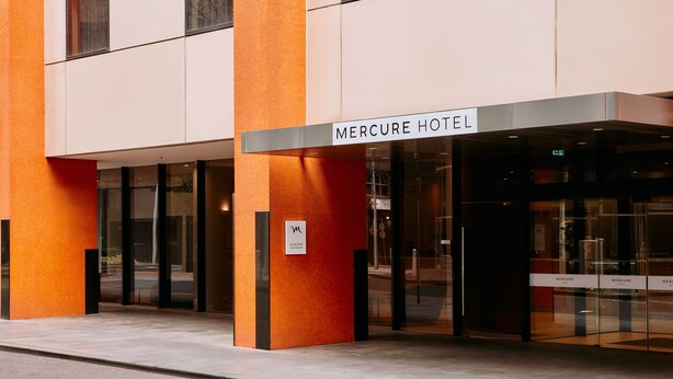 Exterior del hotel Mercure con un diseño moderno, que presenta grandes puertas de vidrio y una señalización destacada.