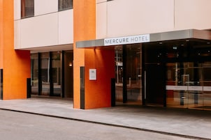 Exterior del hotel Mercure con un diseño moderno, que presenta grandes puertas de vidrio y una señalización destacada.