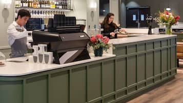 A bar area with a grill station, a counter with a vase of flowers, and shelves with bottles.