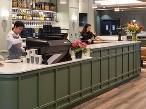 A bar area with a grill station, a counter with a vase of flowers, and shelves with bottles. - Mercure Melbourne Southbank (Southbank)