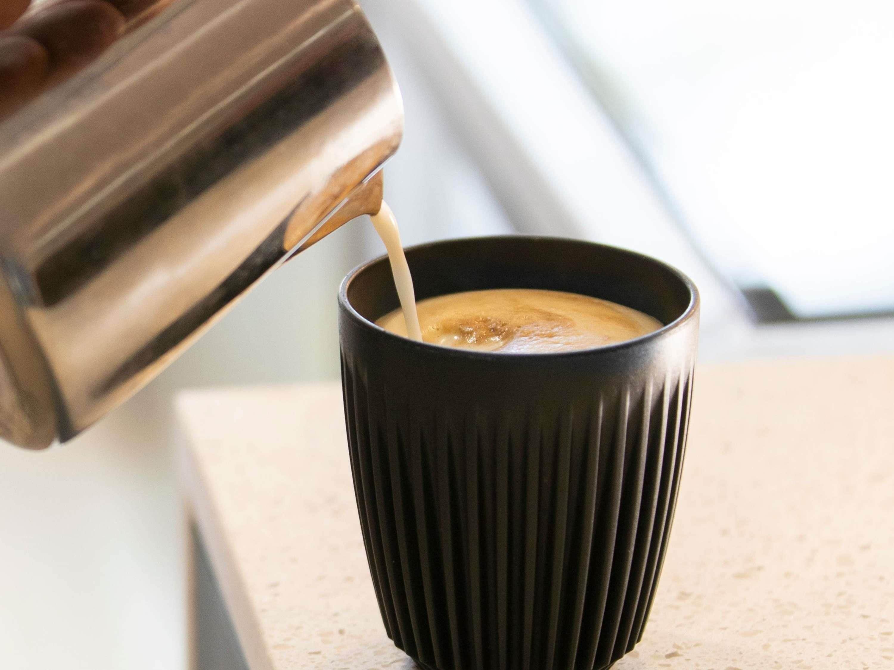 En metallisk espressomaskin som häller kaffe i en svart kopp.