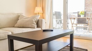 A modern living room with a sofa, a coffee table, and a balcony with outdoor furniture.
