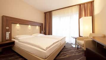 A hotel room with a large bed, a desk, a chair, and a lamp.