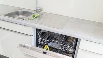 A kitchen with a stainless steel sink, a dishwasher, and a faucet.