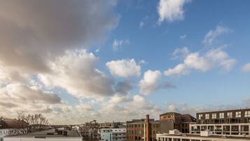 A cityscape with modern buildings, a clear sky, and scattered clouds.