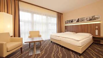 Una camera d'albergo con un letto, una sedia, un tavolo e un'ampia finestra con tende.
