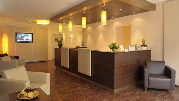 A reception area with a wooden reception desk, a television, and a seating area with a fruit bowl.
