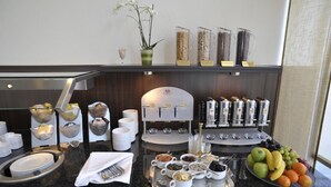 Un buffet de petit-déjeuner proposant une variété d’aliments, des machines à café et un présentoir de fruits.