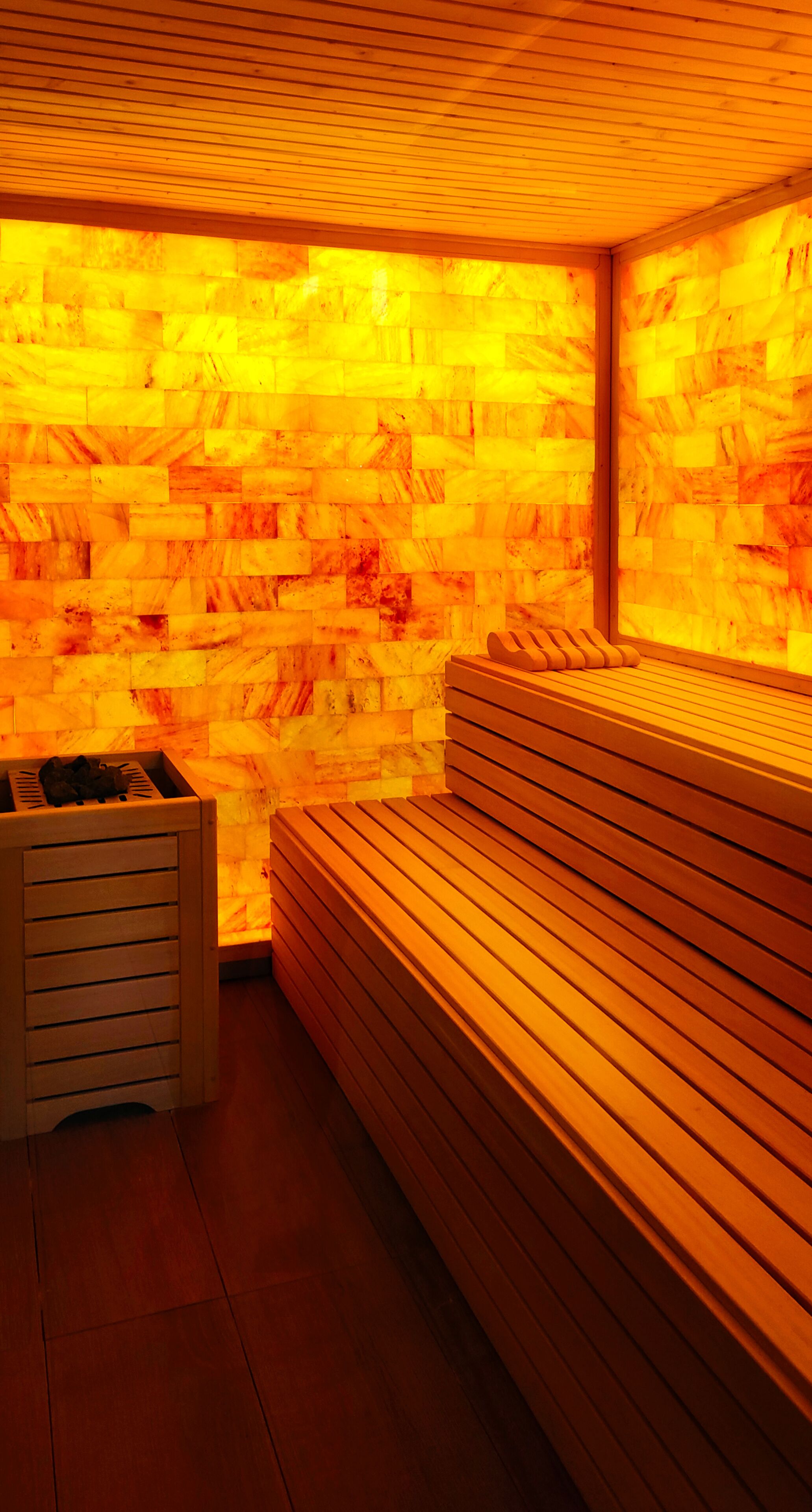 A sauna with wooden benches and a stone wall.