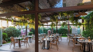 An outdoor dining area with tables and chairs, surrounded by greenery and plants. - Hotel La Laguna Spa And Golf (Rojales)