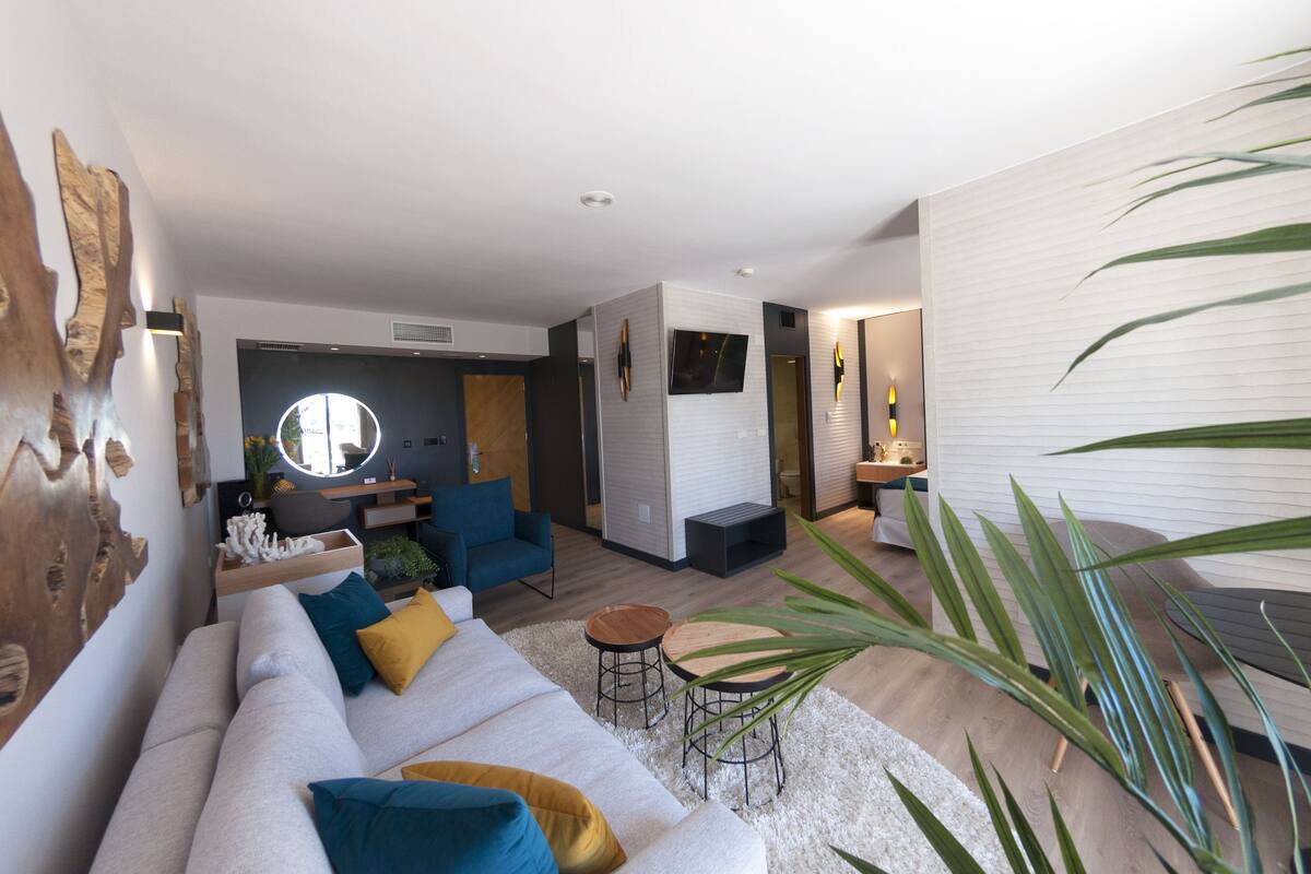 A modern living room with a sofa, chairs, a coffee table, and a TV.