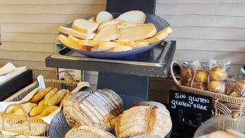 Een bakkerijdisplay met verschillende broden en gebak, waaronder glutenvrije opties.