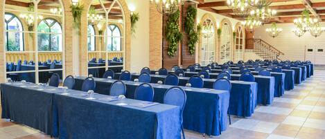 A conference room with rows of tables and chairs, large windows, and a wooden ceiling.