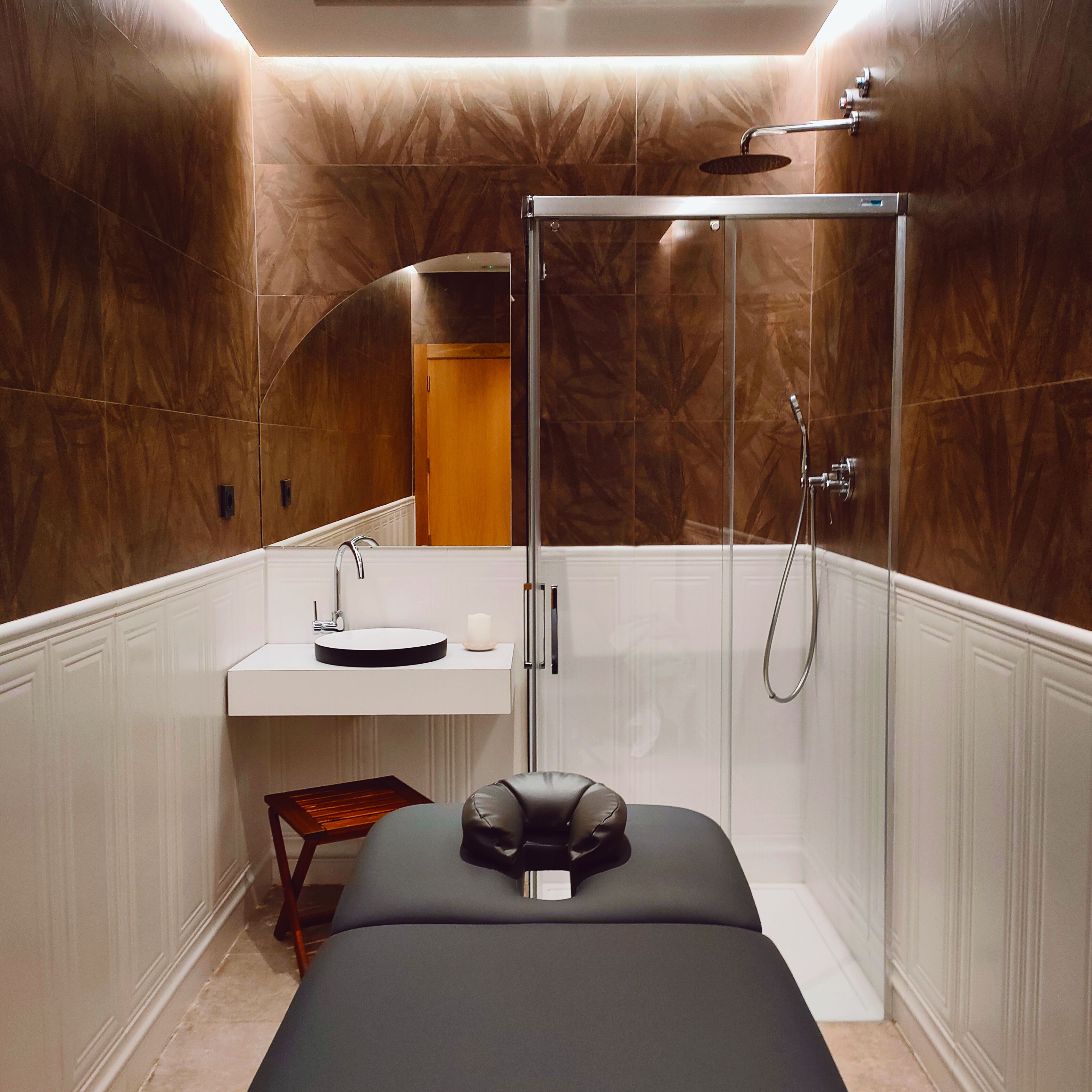 Ein modernes Badezimmer mit begehbarer Dusche, einem runden Waschbecken und einem Massagesessel.