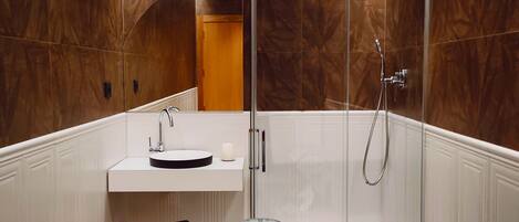 A modern bathroom with a walk-in shower, a round sink, and a massage chair.