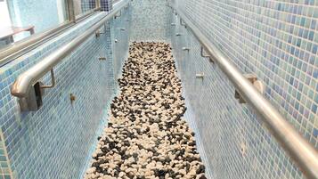 Stroll down the corridor lined with blue mosaic tiles and pebbles, leading to a door.